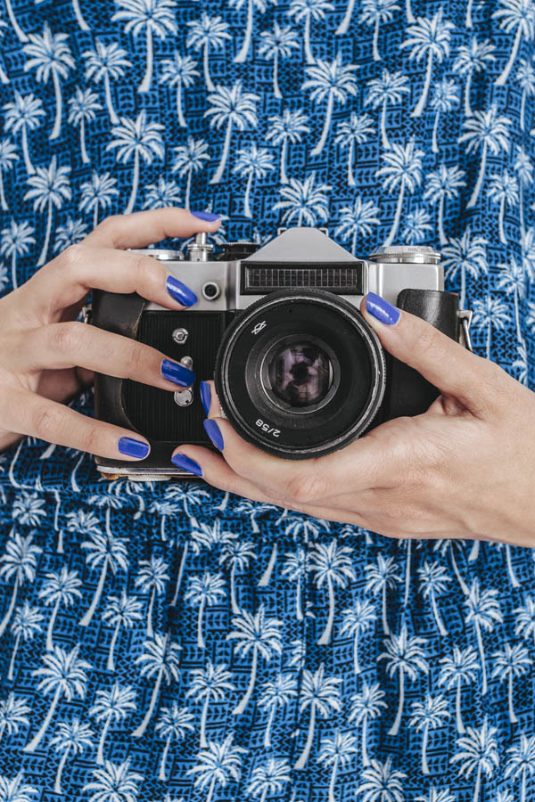 Young Woman Holding a Retro Camera on White Background